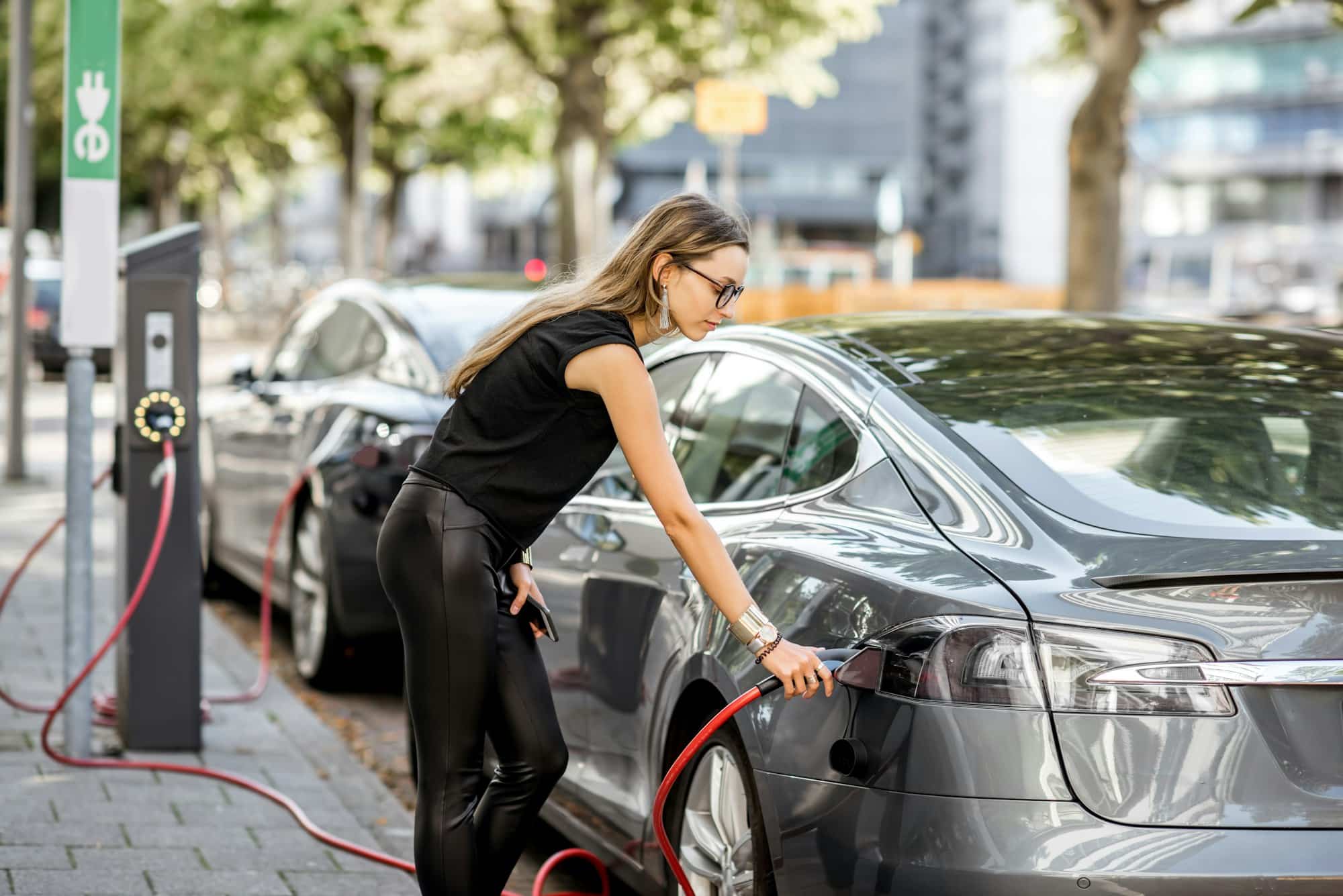 Femme chargeant une voiture électrique à l’extérieur